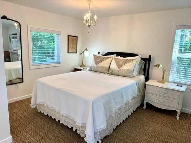 Queen size bed with fine linens, full size mirror and sisal style carpet in bedroom