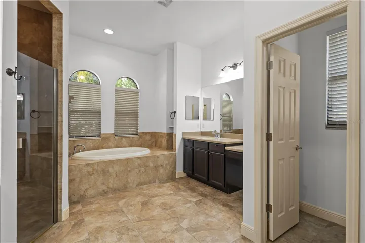 En suite primary bathroom with double sinks, walk in shower, and garden tub
