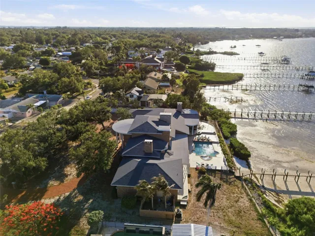 From a westward aerial vantage view highlights the estate architectural presence, capturing three points of the mansion against a spectacular waterfront setting.