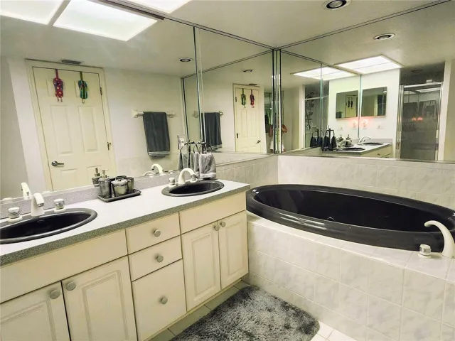 Primary bathroom (3rd bath) with spa tub and walk in shower, dual sinks