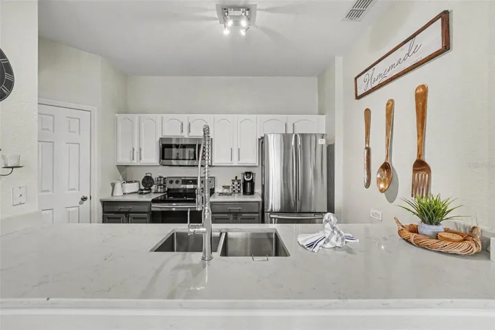 Remodeled kitchen with open layout, stone counters, double sink, stainless appliances, and painted cabinets.