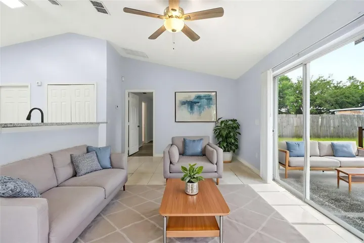 Living room, ceiling fan and tile floors, sliding glass doors, virtually staged