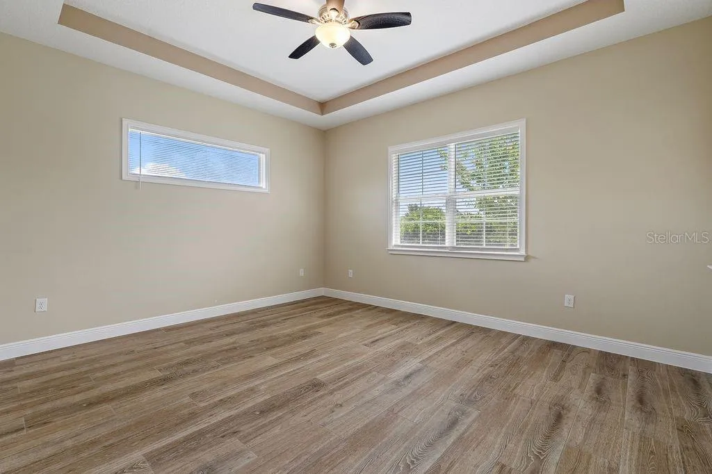 Primary bedroom with tray ceiling and plenty of windows