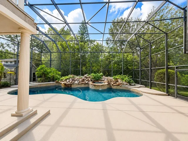The oversized screened pool area was resurfaced w/ a pebble tec finish &amp; retiled, extensive rock waterfalls w/ an auto timer, salt system, remote pool automation system controlling the pool light, 3 waterfalls, a spill over feature &amp; the pool cleaner. French doors lead out to the screened lanai &amp; full pool bath, plus an outdoor kitchen w/ a grill &amp; sink, all surrounded by mature woods.