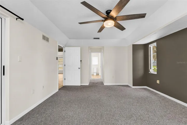 Primary bedroom with hallway to dual walk in closets and ensuite bathroom