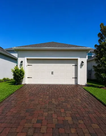 Oversized 2 car garage with paver driveway located behind house