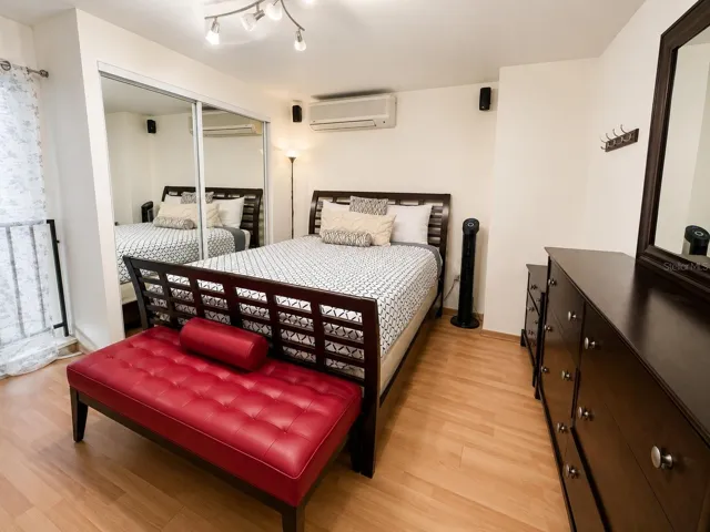 Spacious loft bedroom with mirrored closet doors and mini-split air conditioning.