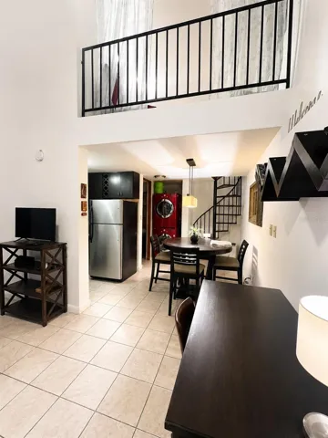 Open-concept living, dining and kitchen area with soaring ceilings and loft above.