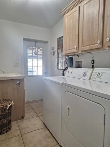 indoor laundry room off garage with utility sink and storage cabinets