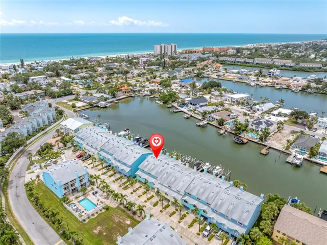 A bird's-eye look at life in Sunset Bay — a row of pastel townhomes tucked along the Intracoastal, docks lined with boats, and the Gulf shimmering in the distance. This is the view that sells the lifestyle before you even step inside.