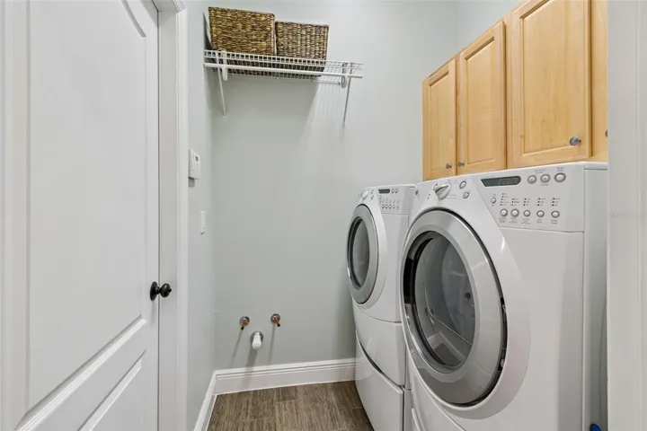 The laundry room is tucked behind the kitchen, comes with washer and dryers on pedestal storage.  The space is already pre-plumbed for a laundry sink.