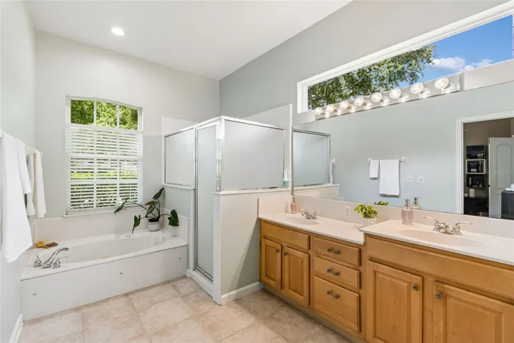 Sunny primary bathroom with tiled shower and whirlpool tub