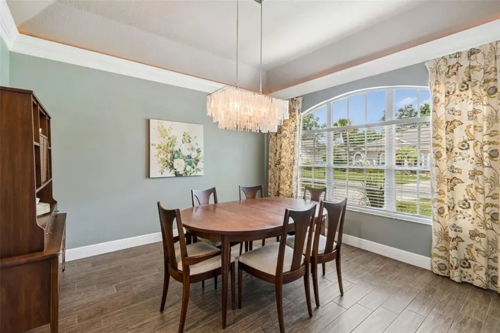 Elegant formal dining room has a tray ceiling with crown molding and rope light accents