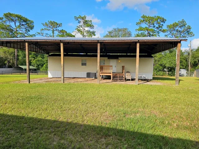 Front of home with horse turnout and paddock area to the right and back gate to the left.