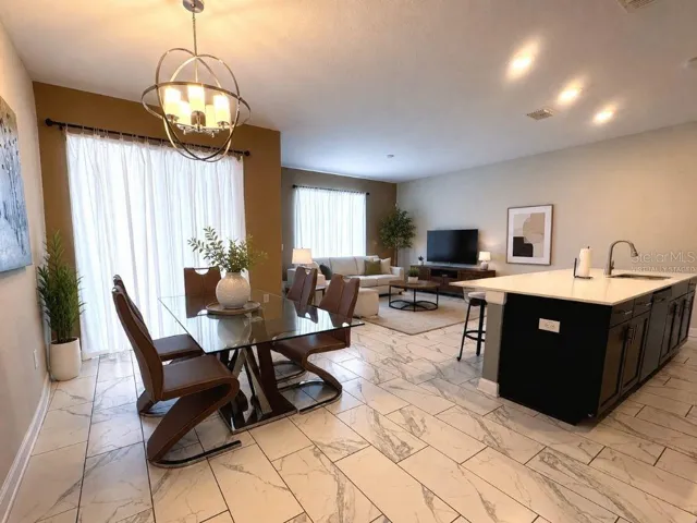 Virtually staged open-concept living, dining, and kitchen area showcasing the home’s bright layout, stylish finishes, and comfortable gathering spaces.