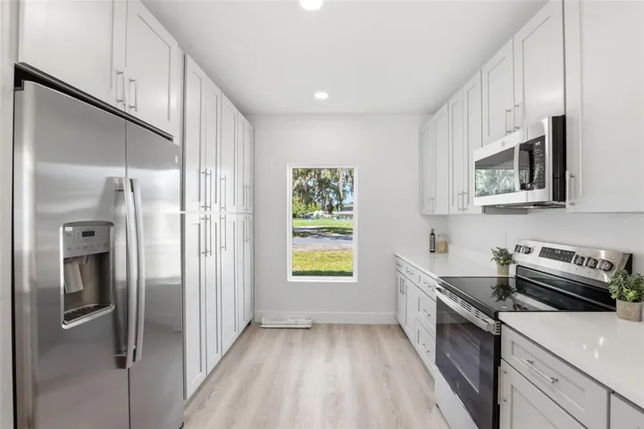 Kitchen view with granite countertops, stainless steel appliances, and frontyard-facing natural light.