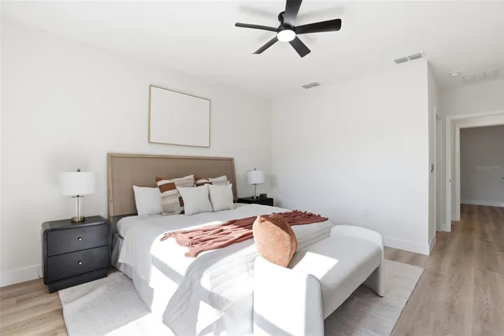 Primary bedroom with ceiling fan, neutral finishes, and a clean new construction design.