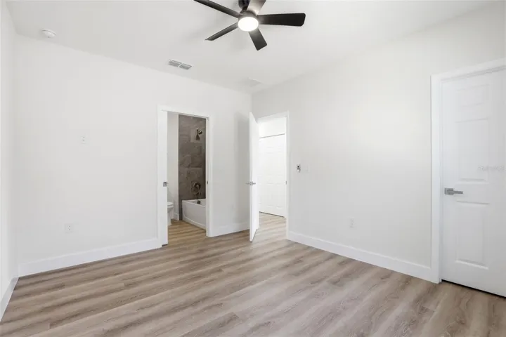 Secondary bedroom with modern flooring, ceiling fan, and neutral finishes.