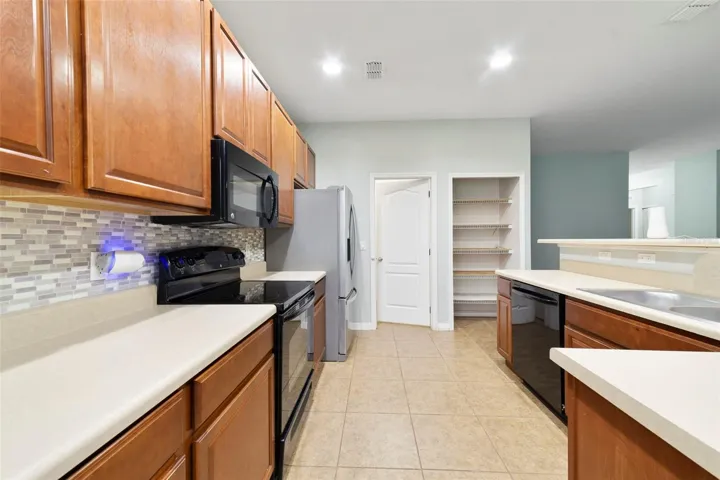 The Kitchen is thoughtfully designed with an abundance of cabinetry and counter space, a stylish tile backsplash, BREAKFAST BAR, and a convenient closet pantry.