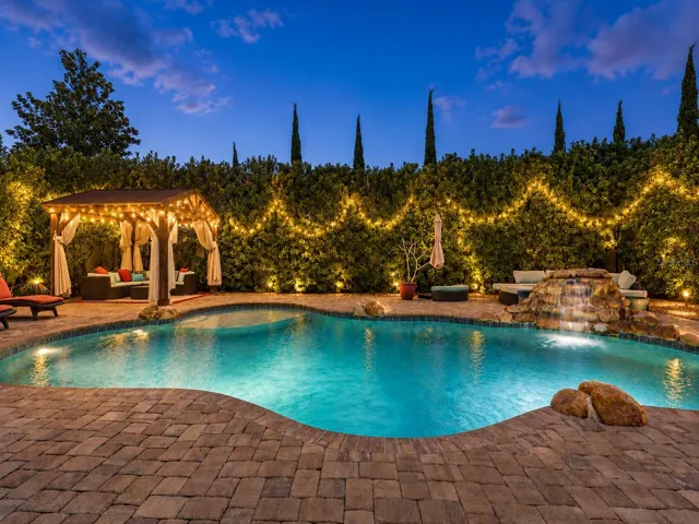The home SHOW STOPPER-swimming pool with rock water fall, brick paver decking, private cabana, shrubs for privacy, and more.
