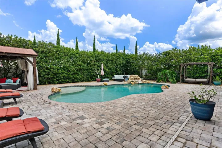 The home SHOW STOPPER-swimming pool with rock water fall, brick paver decking, private cabana, shrubs for privacy, and more.