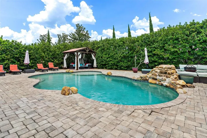 The home SHOW STOPPER-swimming pool with rock water fall, brick paver decking, private cabana, shrubs for privacy, and more.
