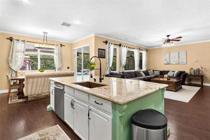 Kitchen features stainless steel appliances, granite countertops, stylish backsplash, cooper sink, and large center island while overlooking dinette and family room.