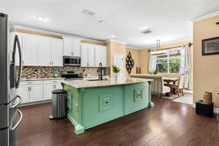 Kitchen features stainless steel appliances, granite countertops, stylish backsplash, cooper sink, and large center island while overlooking dinette and family room.