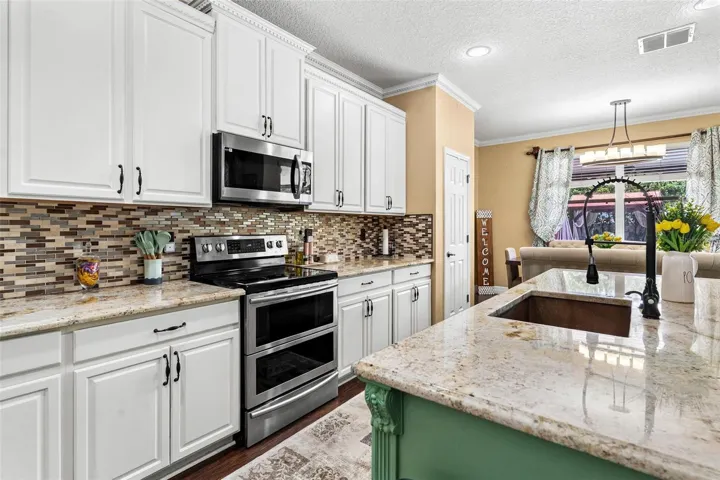 Kitchen features stainless steel appliances, granite countertops, stylish backsplash, cooper sink, and large center island while overlooking dinette and family room.