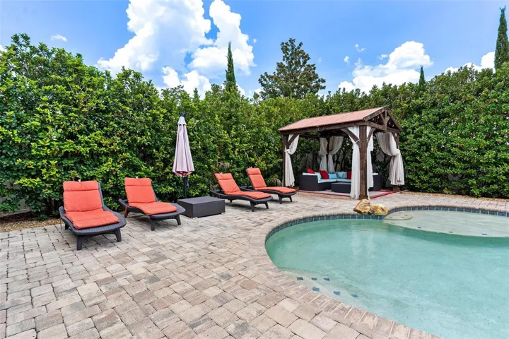 The home SHOW STOPPER-swimming pool with rock water fall, brick paver decking, private cabana, shrubs for privacy, and more.