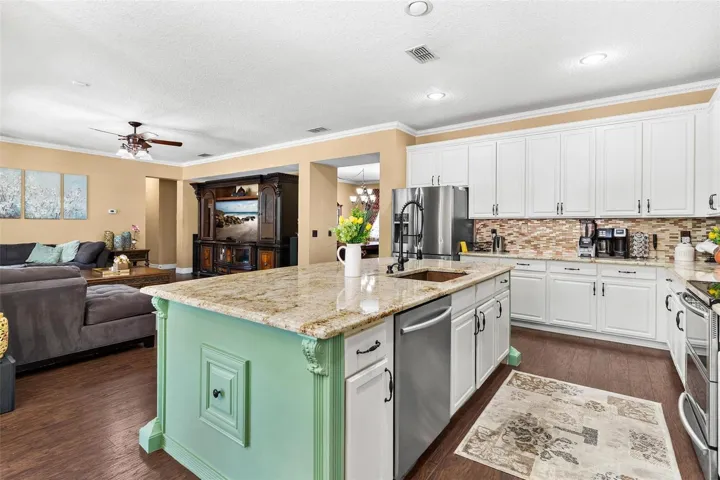 Kitchen features stainless steel appliances, granite countertops, stylish backsplash, cooper sink, and large center island while overlooking dinette and family room.