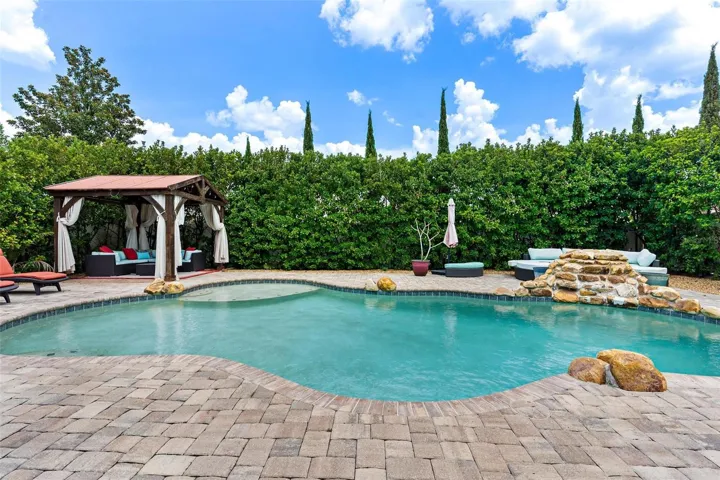The home SHOW STOPPER-swimming pool with rock water fall, brick paver decking, private cabana, shrubs for privacy, and more.