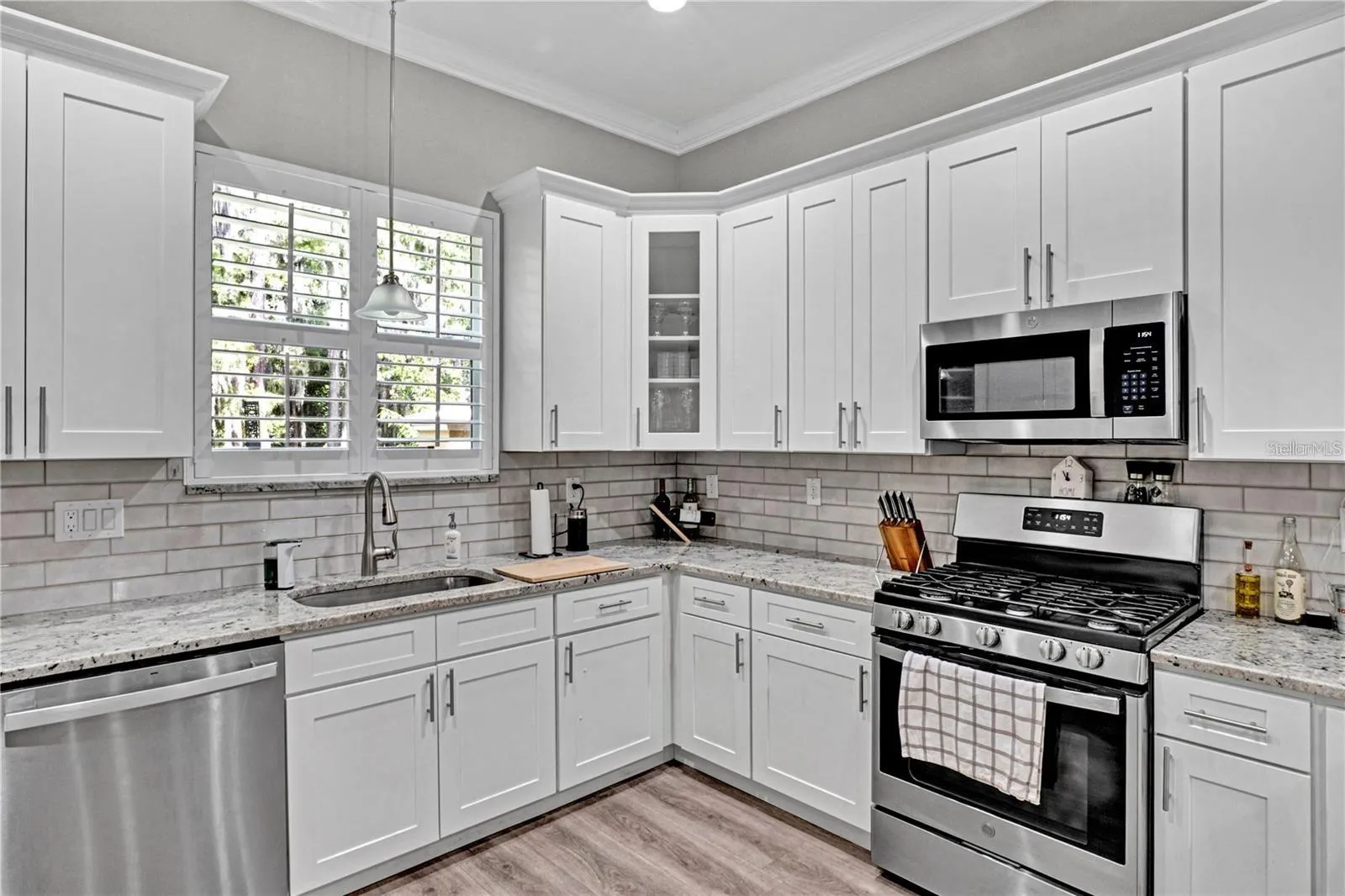 Cook with ease using the premium gas range. The kitchen is beautifully finished with a classic subway tile backsplash, a deep under-mount sink, and elegant glass-front corner cabinetry