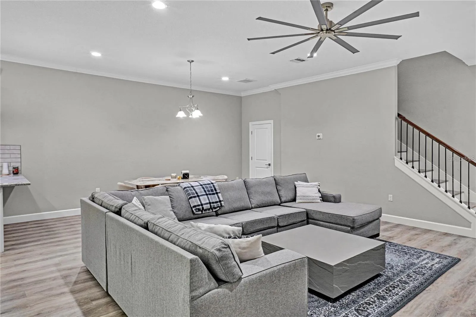 The expansive, open-concept main floor features durable wood-look flooring, modern recessed lighting, and a massive ceiling fan designed to keep the entire living space cool and comfortable.