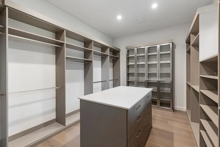 Expansive walk-incloset with stone-topped island and custom storage system