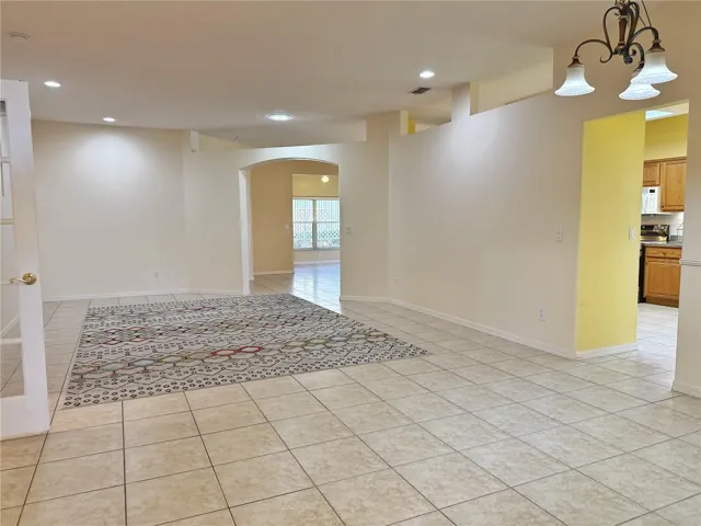 Living room with entry to the Kitchen and Dinette and view of the Family and Florida room, ceramic tile flooring, French doors to den/study/ bedroom 3