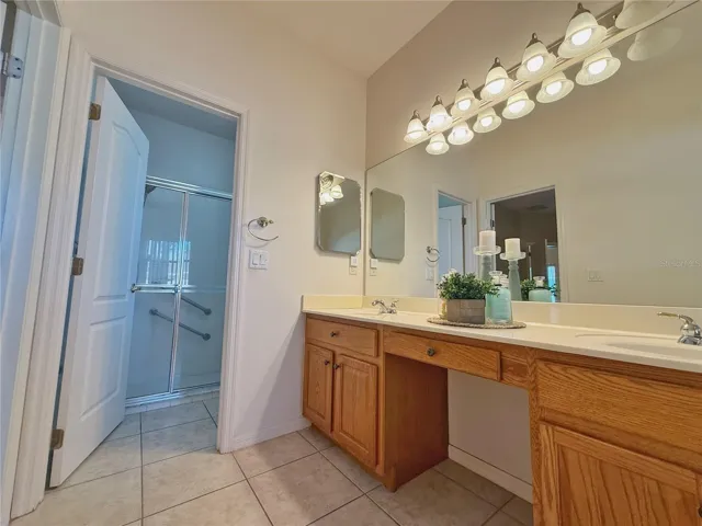 Primary Bathroom with solid wood cabinets, vanity space, dual sinks, garden tub with separate shower, water closet, ceramic tile flooring