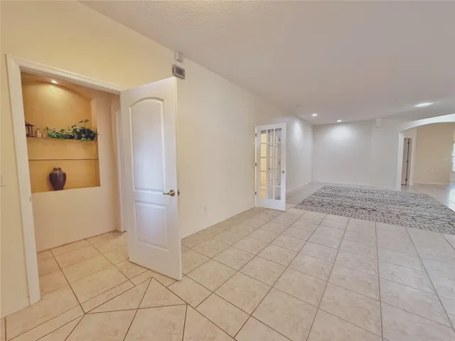 View of doored entry to Bedroom 2 and Bathroom 2 with decorative niche, double French doors into den /study/bedroom 3 and living room