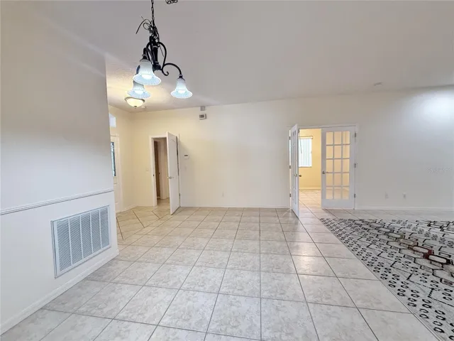 Dining room with view of Doored entry to Bedroom 2 and Bath 2 and double French doors into Den/stidy/ Bedroom 3, ceramic tile flooring throughout