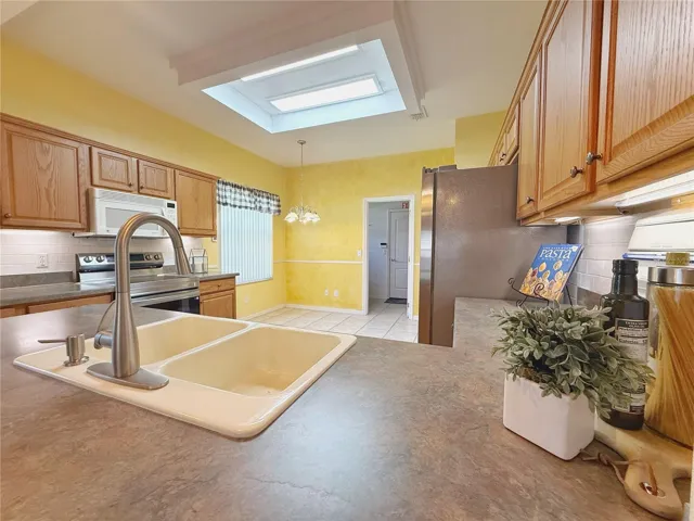 View form bar top seating of Kitchen and dinette, solid wood cabinets with under cabinet lighting, ceramic tile flooring, tile backsplash