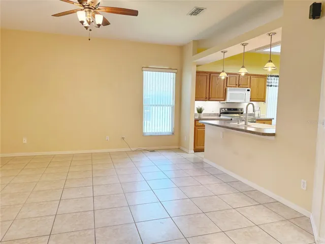 Living room with view of the Kitchens bar top seating with pendant lighting, solid wood cabinets, decorative shelves