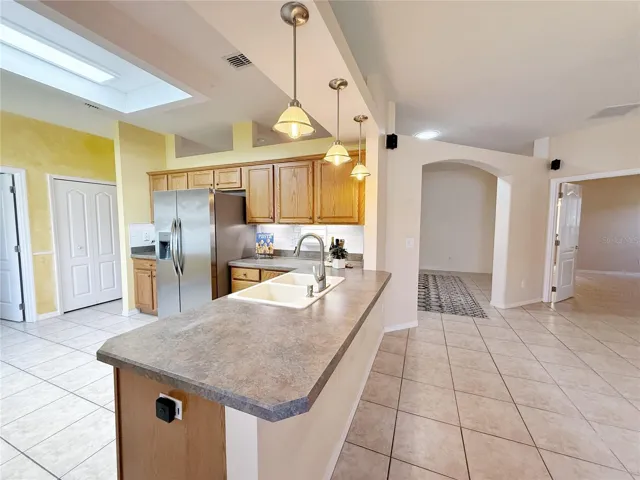 View of Kitchen from family room with panty, view of Primary bedroom and Living Room, bar top seating with pendant lighting, decorative shelf, ceramic tile flooring