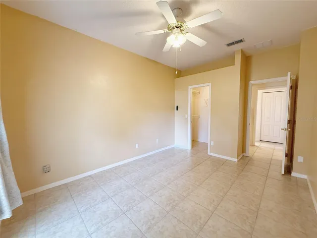 Bedroom 2 with walk in closet, ceramic tile flooring, decorative shelf