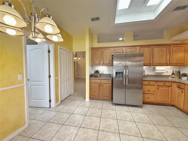 Dinette with view of Kitchen, pantry and laundry room and walk through to Dining Room, ceramic tile flooring, solid wood cabinets with under cabinet lighting, tile backsplash
