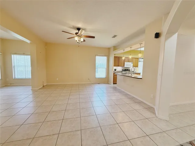Family room with view of Kitchen with bar top seating and pendant lighting, view of the sitting room or Florida room, ceramic tile flooring, open floor plan