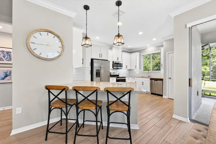 The kitchen combines style and function with STAINLESS STEEL APPLIANCES, sleek granite countertops, SUBWAY TILE BACKSPLASH, upgraded hardware and fixtures, abundant storage and a window above the sink that fills the space with natural light while showcasing the peaceful views.