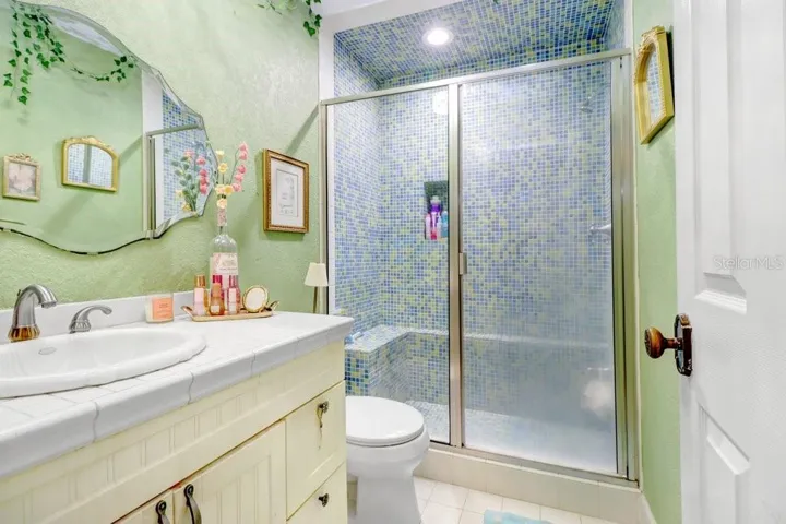 Fun upstairs full bathroom with floor to ceiling mosaic tiled shower which includes seat and shampoo nook.