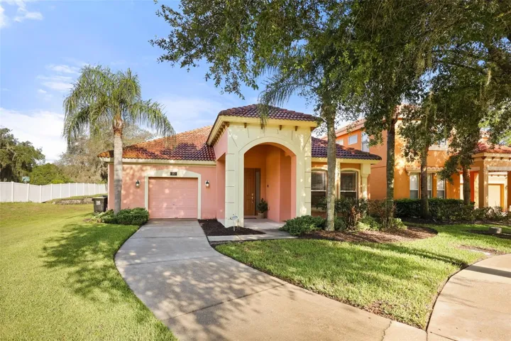 Attractive corner-lot location with mature landscaping, paver driveway, and inviting covered front entry.