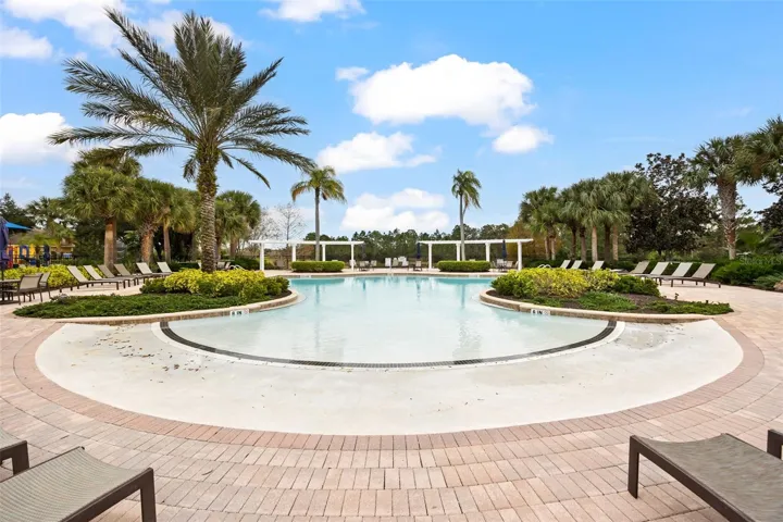 Resort-style community pool surrounded by tropical landscaping, sun loungers, and relaxing outdoor spaces.