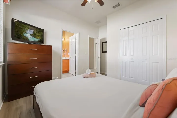 Comfortable queen guest bedroom featuring vaulted ceilings, laminate flooring, and a private en-suite bathroom.
